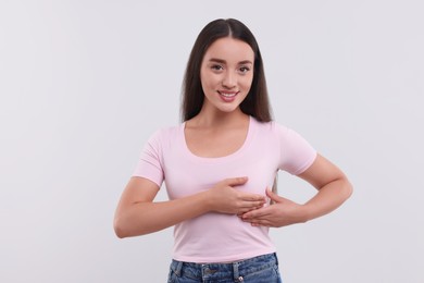 Photo of Beautiful young woman doing breast self-examination on white background