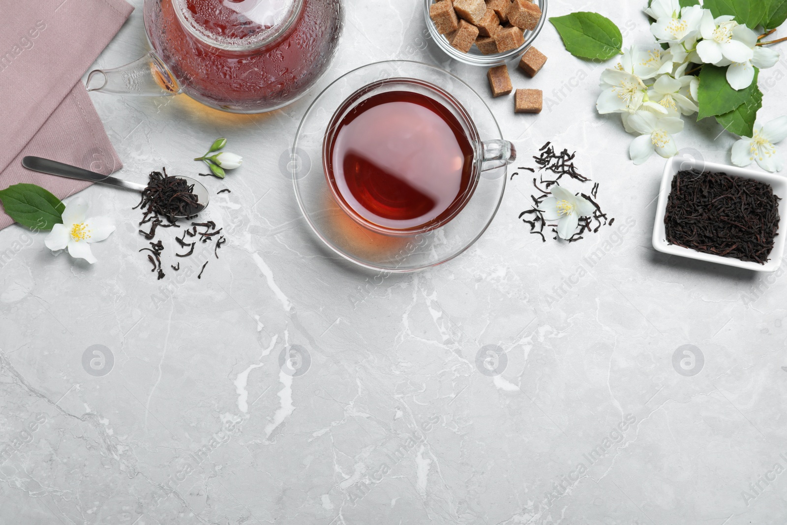 Photo of Flat lay composition with tea and fresh jasmine flowers on light grey marble table. Space for text