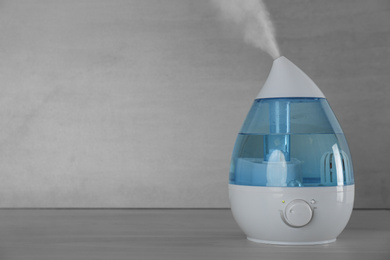 Photo of Modern air humidifier on table against grey background. Space for text