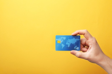 Photo of Young man holding credit card on color background