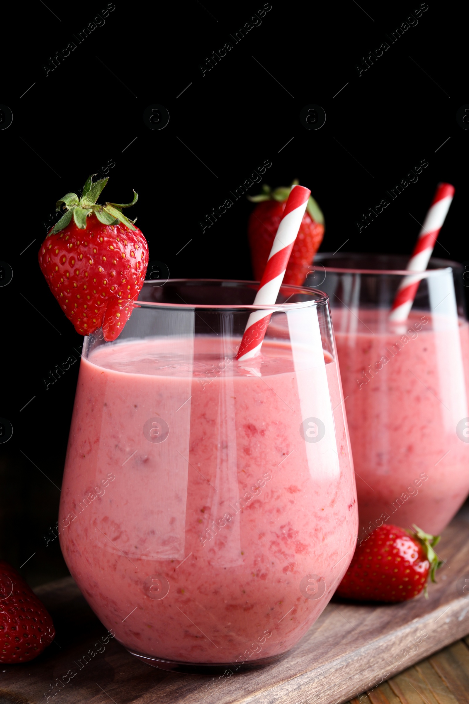 Photo of Tasty strawberry smoothies in glasses on wooden board