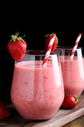 Tasty strawberry smoothies in glasses on wooden board