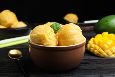 Photo of Yummy mango ice cream in bowl on black wooden table