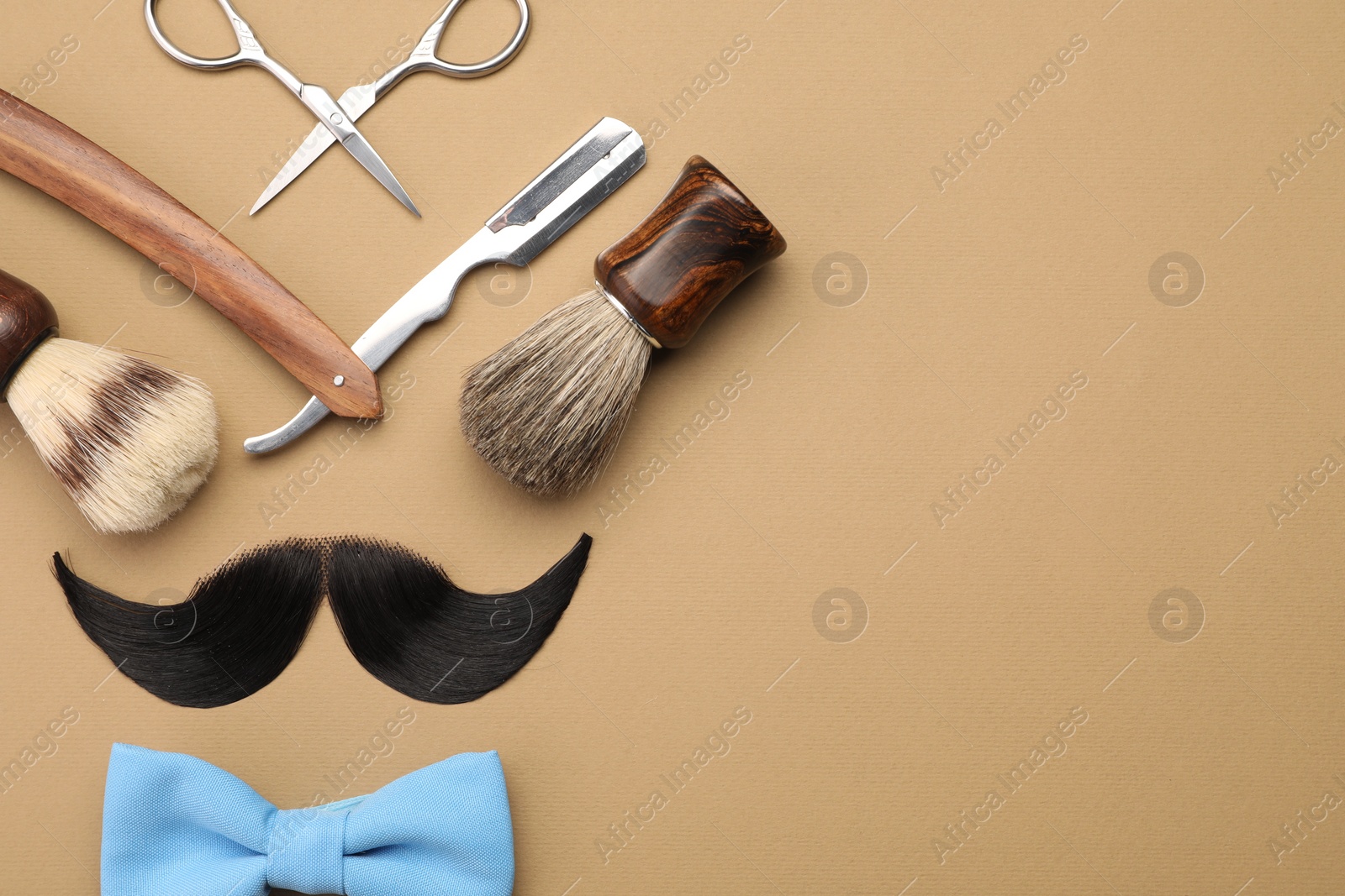 Photo of Artificial moustache and barber tools on beige background, flat lay. Space for text