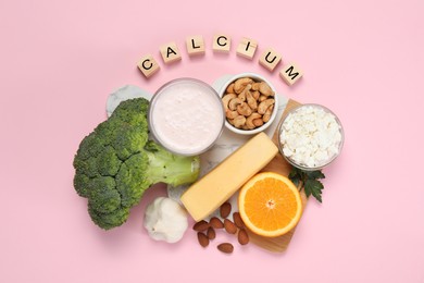 Photo of Food high in calcium. Different products and wooden cubes on pink background, flat lay