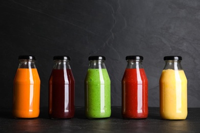 Photo of Bottles with delicious colorful juices on black table