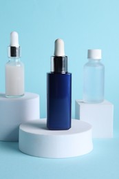 Bottles of cosmetic serum on light blue background