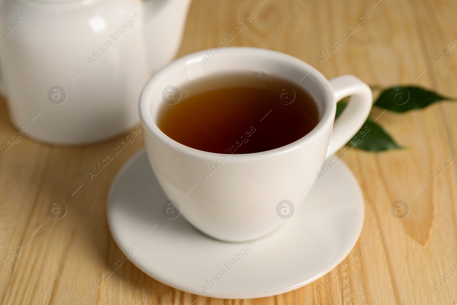 Photo of Tasty tea in cup on light wooden table, closeup