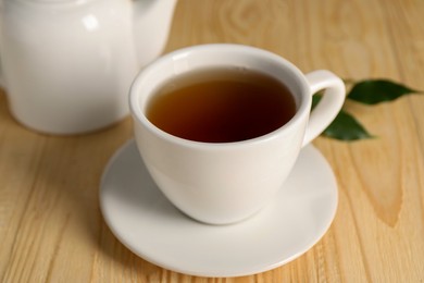 Photo of Tasty tea in cup on light wooden table, closeup