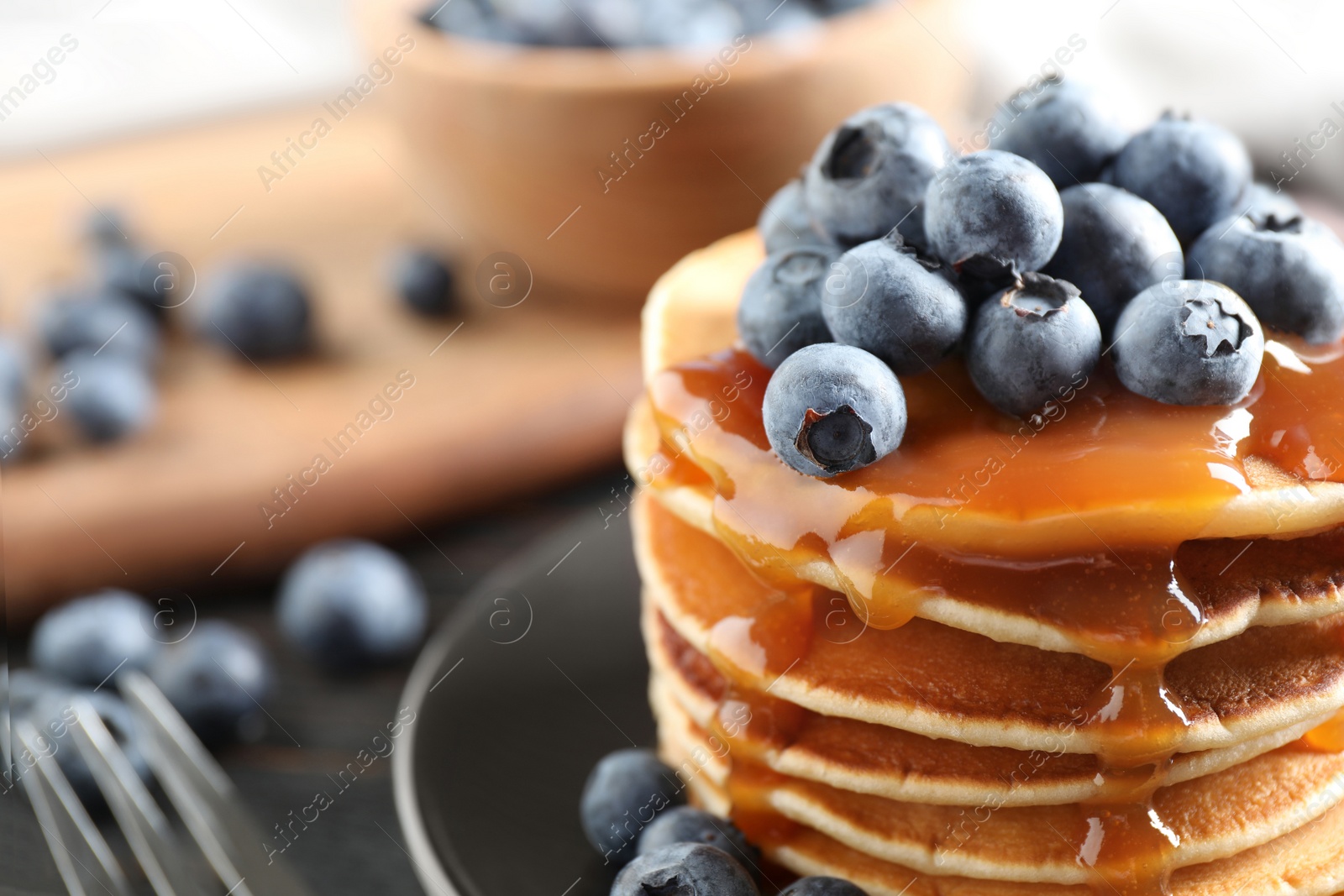 Photo of Delicious pancakes with fresh blueberries and syrup on table, closeup