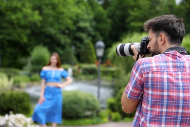 Photographer taking photo of woman with professional camera in park