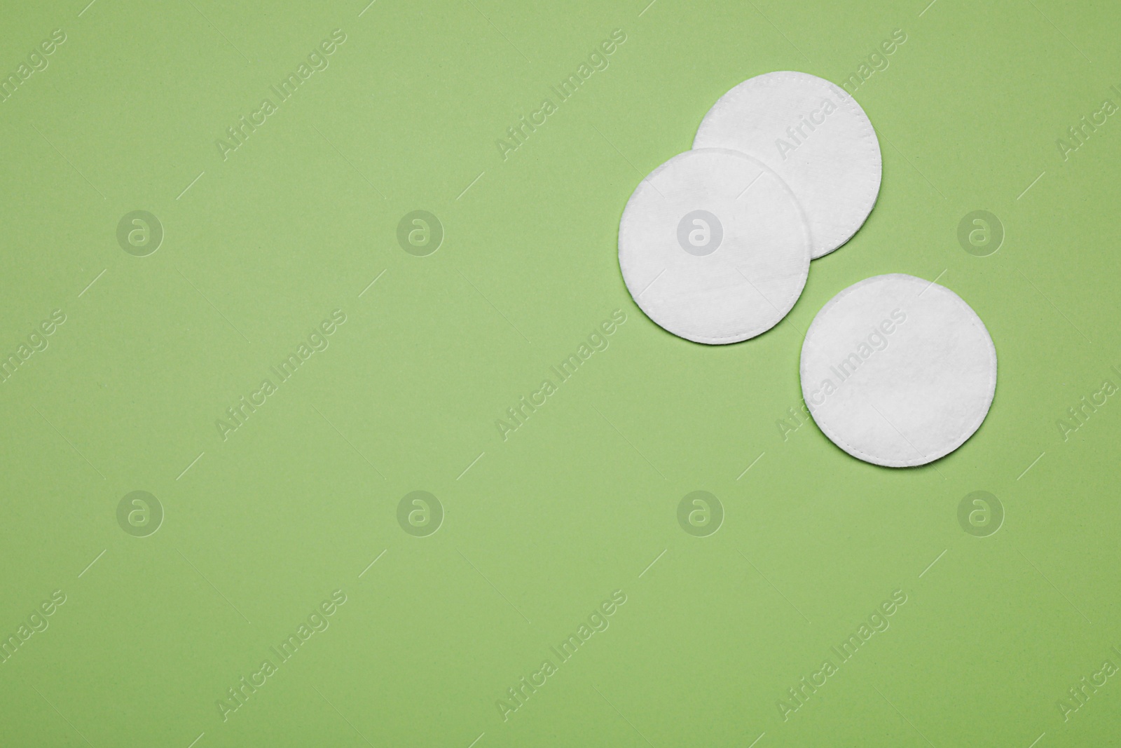 Photo of Cotton pads on green background, flat lay. Space for text