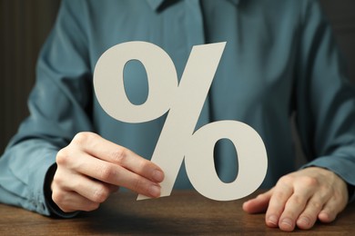 Woman holding percent sign at wooden table, closeup