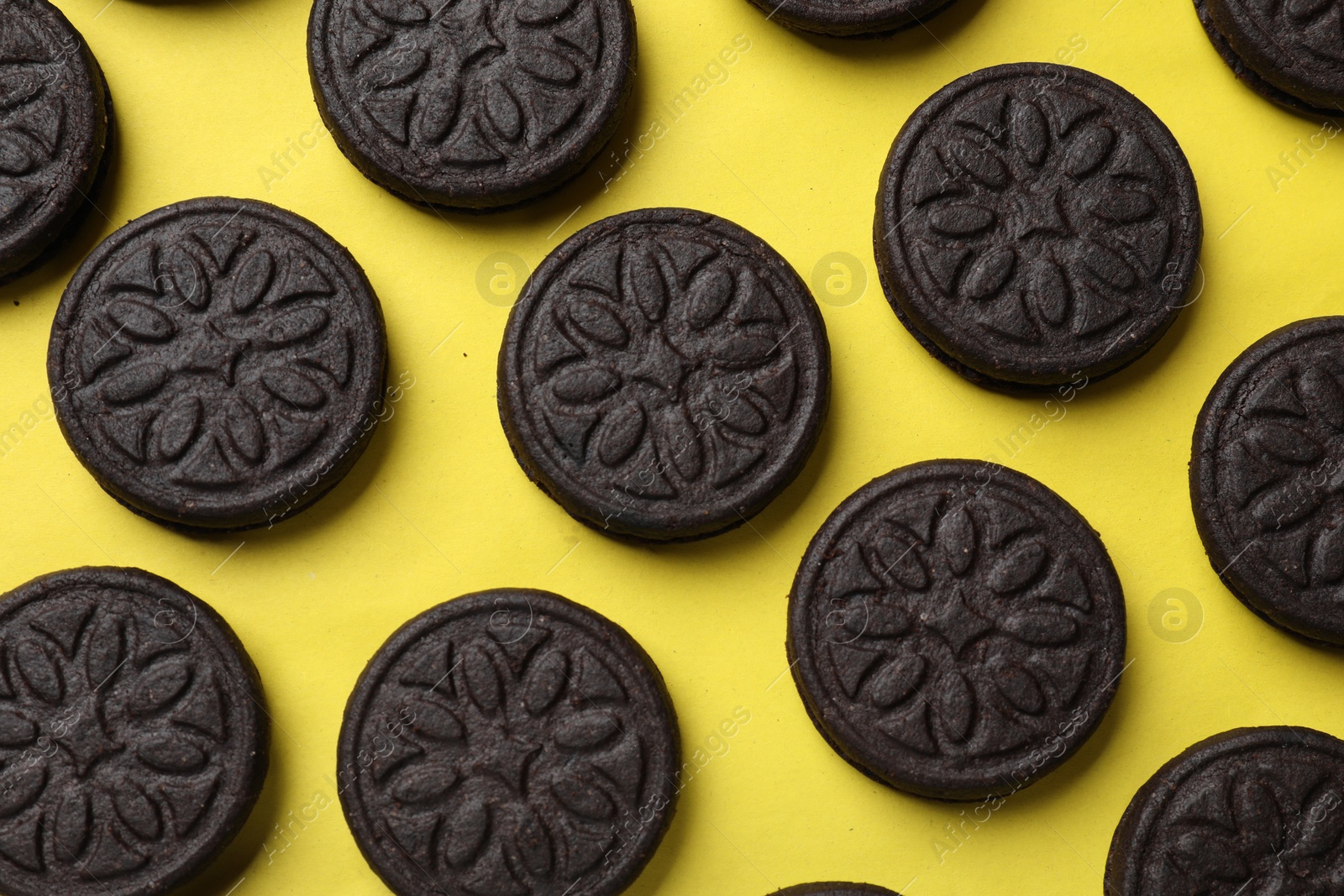 Photo of Tasty sweet sandwich cookies on yellow background, flat lay