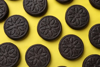 Tasty sweet sandwich cookies on yellow background, flat lay