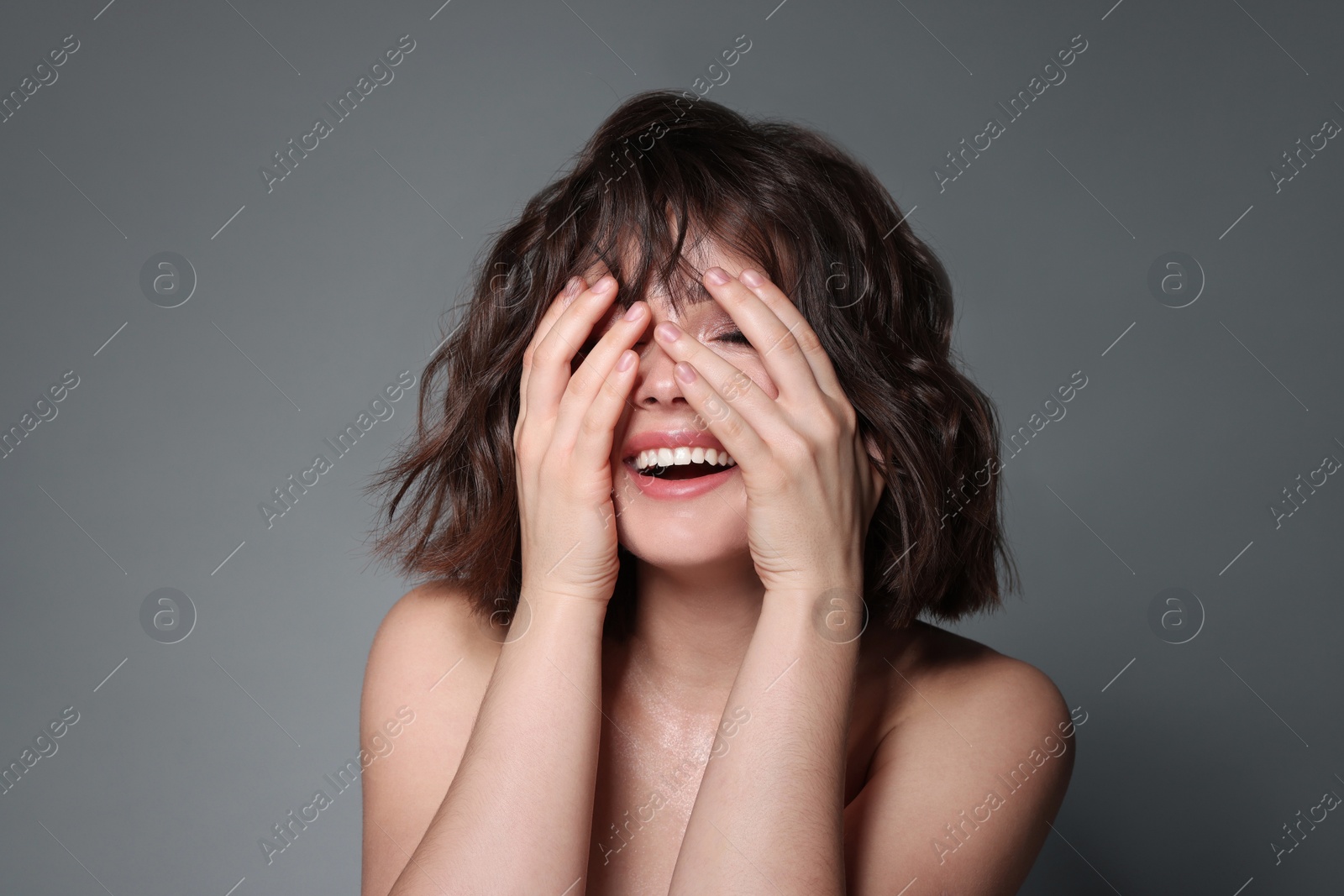 Photo of Beautiful young woman with wavy hairstyle on grey background