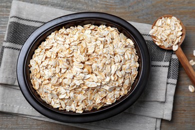 Photo of Bowl and spoon with oatmeal on wooden table, flat lay