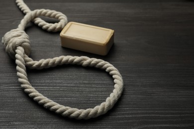 Photo of Rope noose and soap bar on dark wooden table