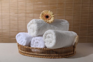 Rolled terry towels and flower on white table indoors