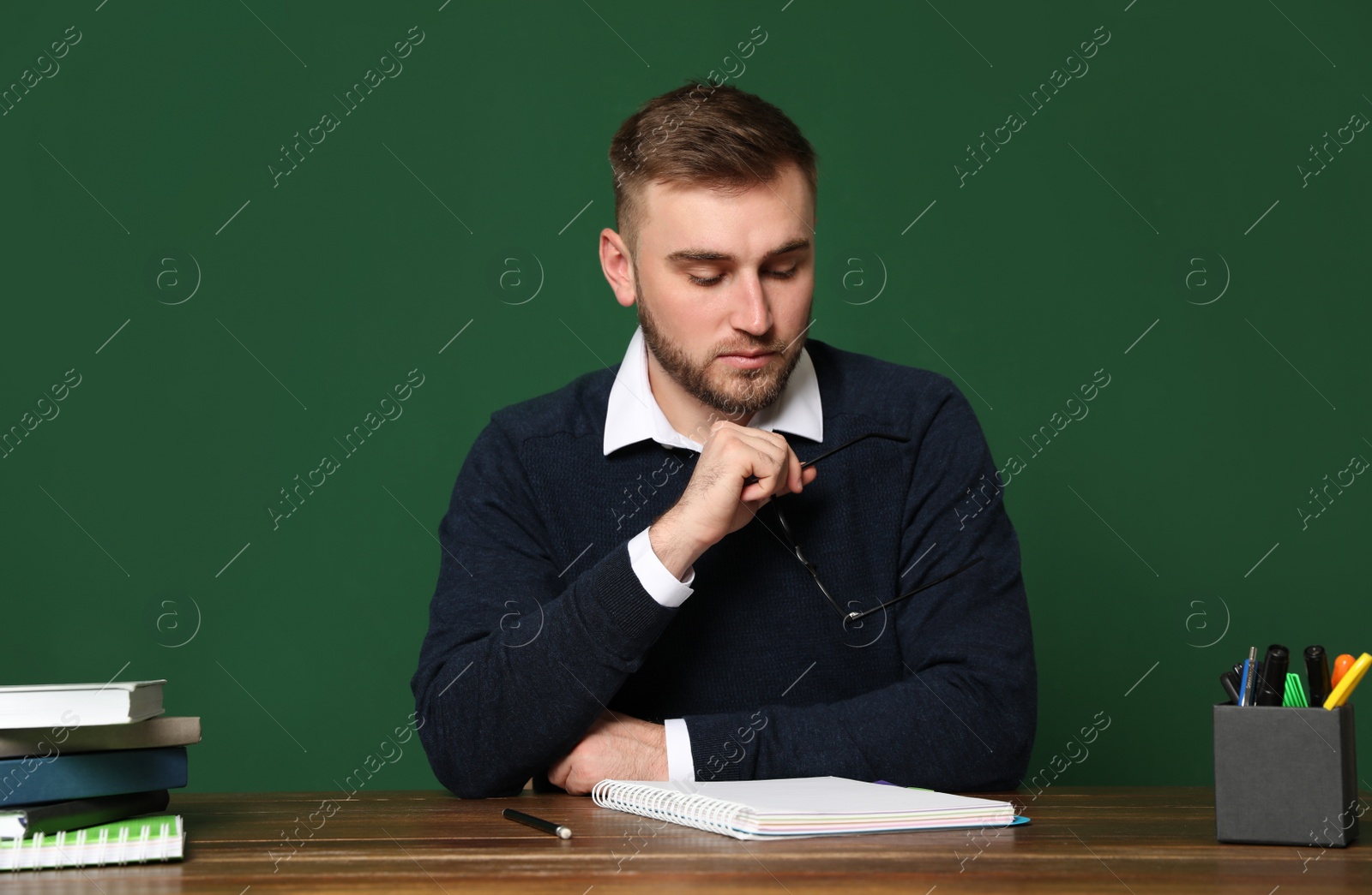 Photo of Portrait of young teacher at table against green background