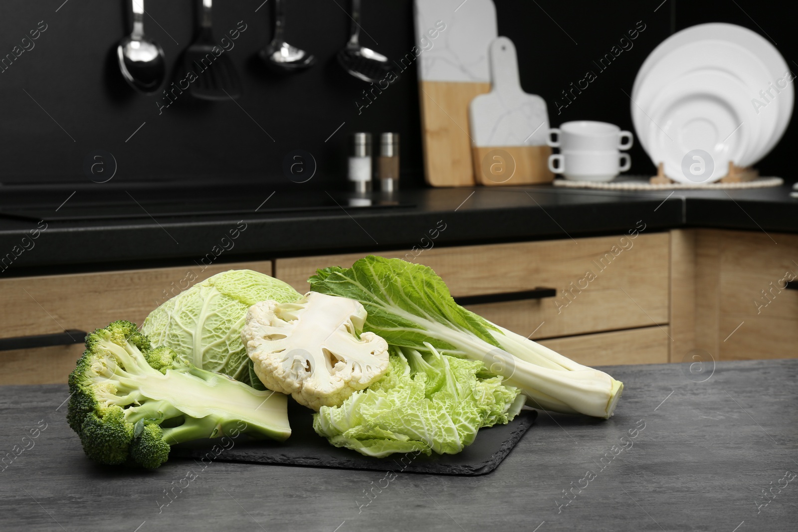 Photo of Different types of cut cabbage on grey table in kitchen