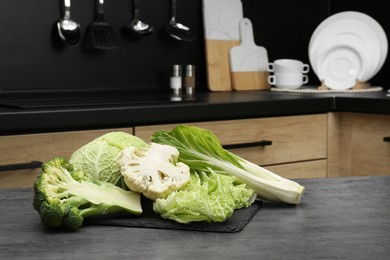 Photo of Different types of cut cabbage on grey table in kitchen