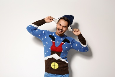 Young man in Christmas sweater and hat on white background