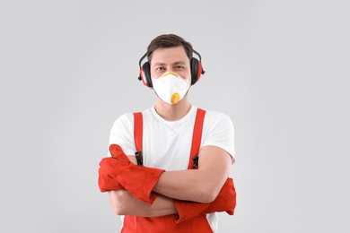 Male industrial worker in uniform on light background. Safety equipment