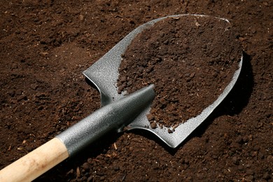 Photo of Metal shovel on fertile soil. Gardening tool