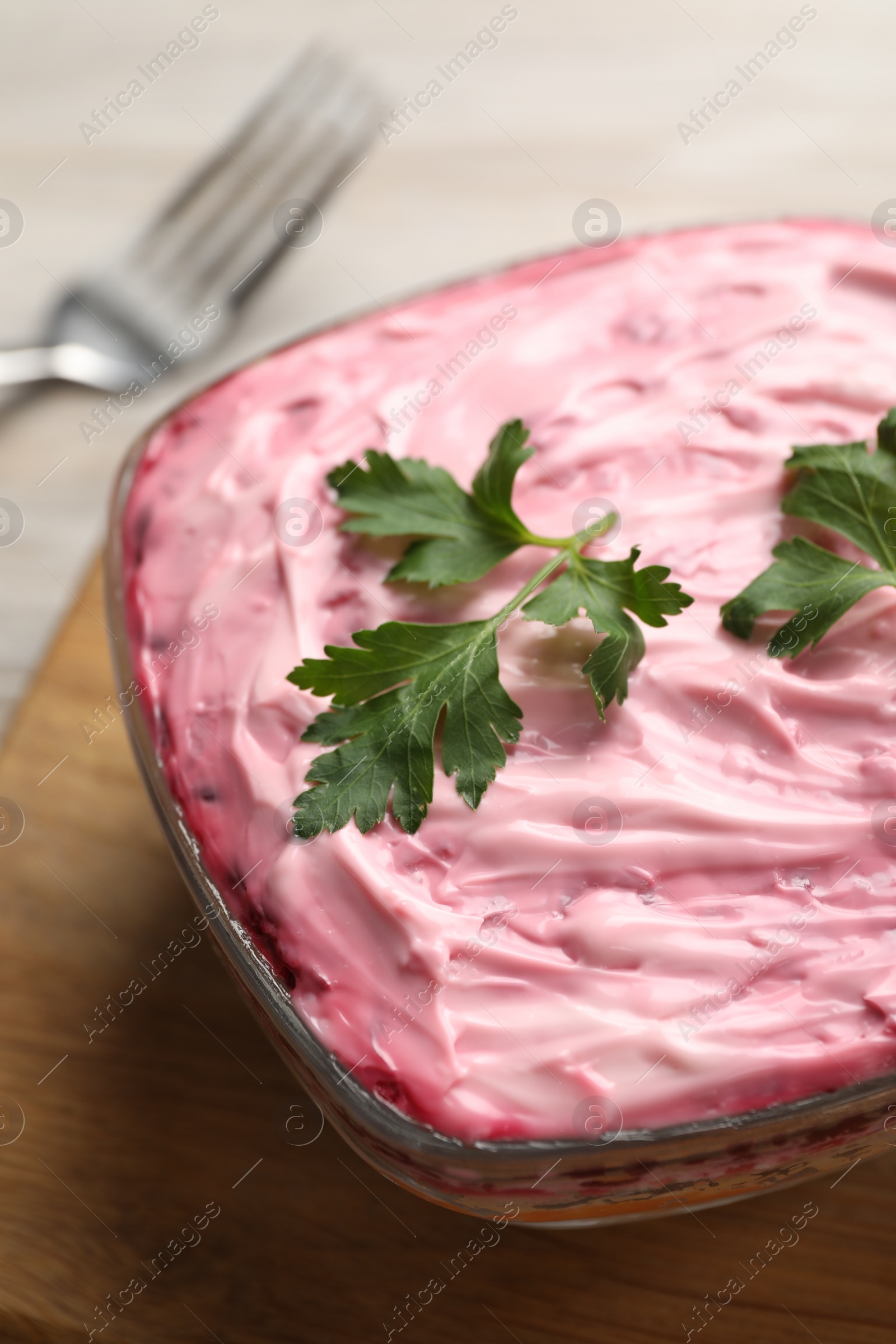 Photo of Herring under fur coat on wooden table, closeup. Traditional Russian salad