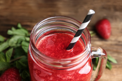 Photo of Tasty strawberry smoothie in mason jar on table, closeup