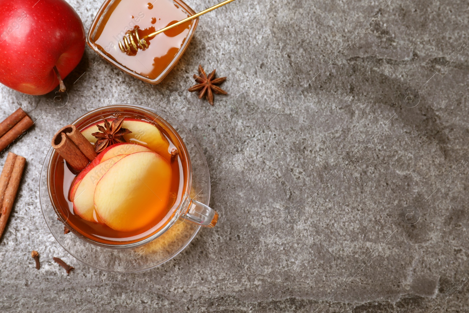 Photo of Aromatic hot mulled cider on grey table, flat lay. Space for text