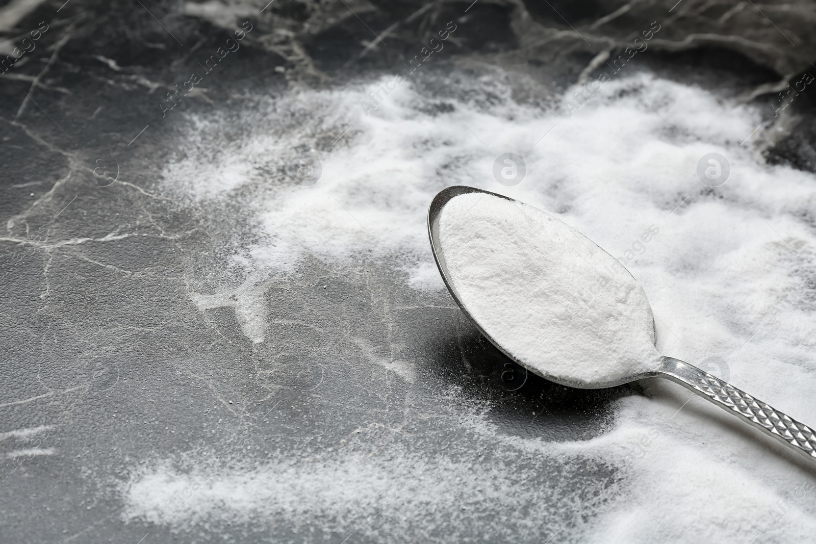 Photo of Spoon with baking soda on grey background, closeup. Space for text