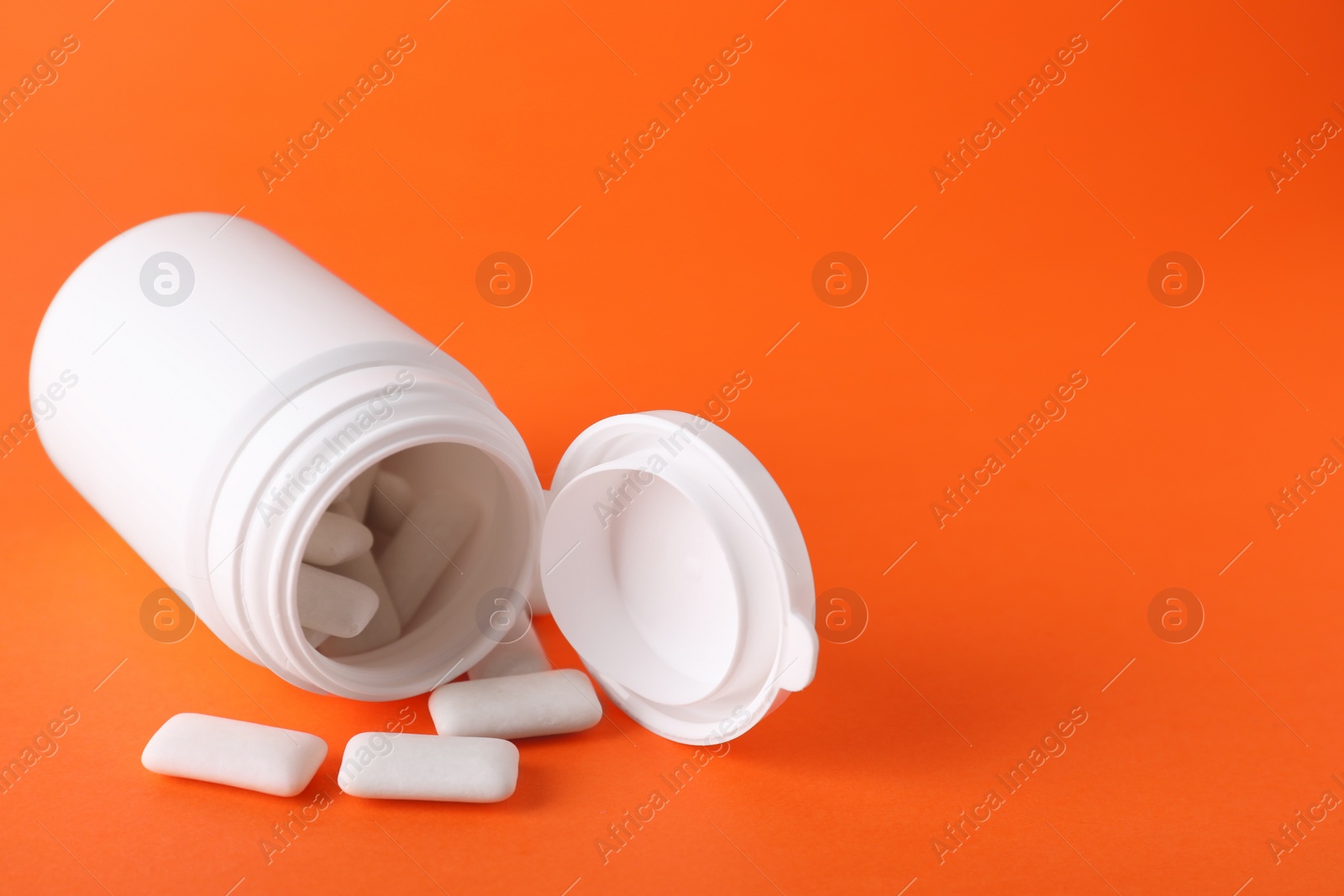 Photo of Jar with chewing gums on orange background. Space for text