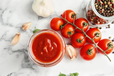 Flat lay composition with jar of tasty tomato sauce on marble table