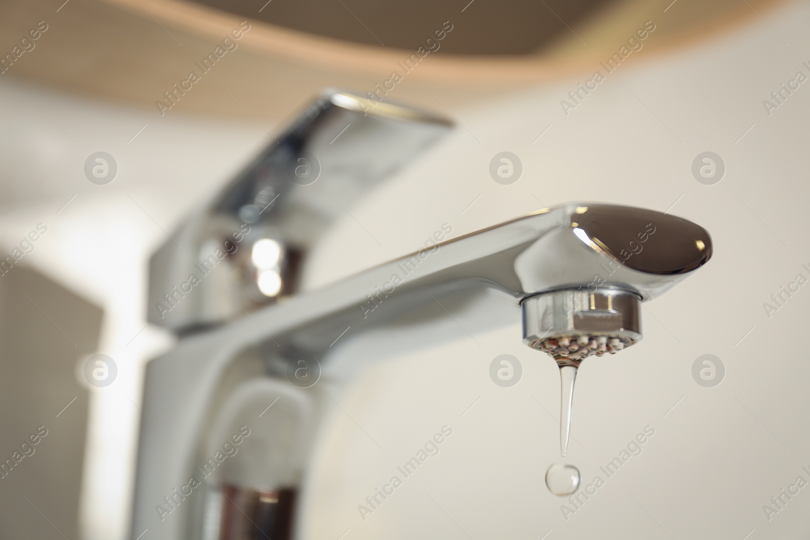 Photo of Water drop falling down from tap on blurred background, closeup