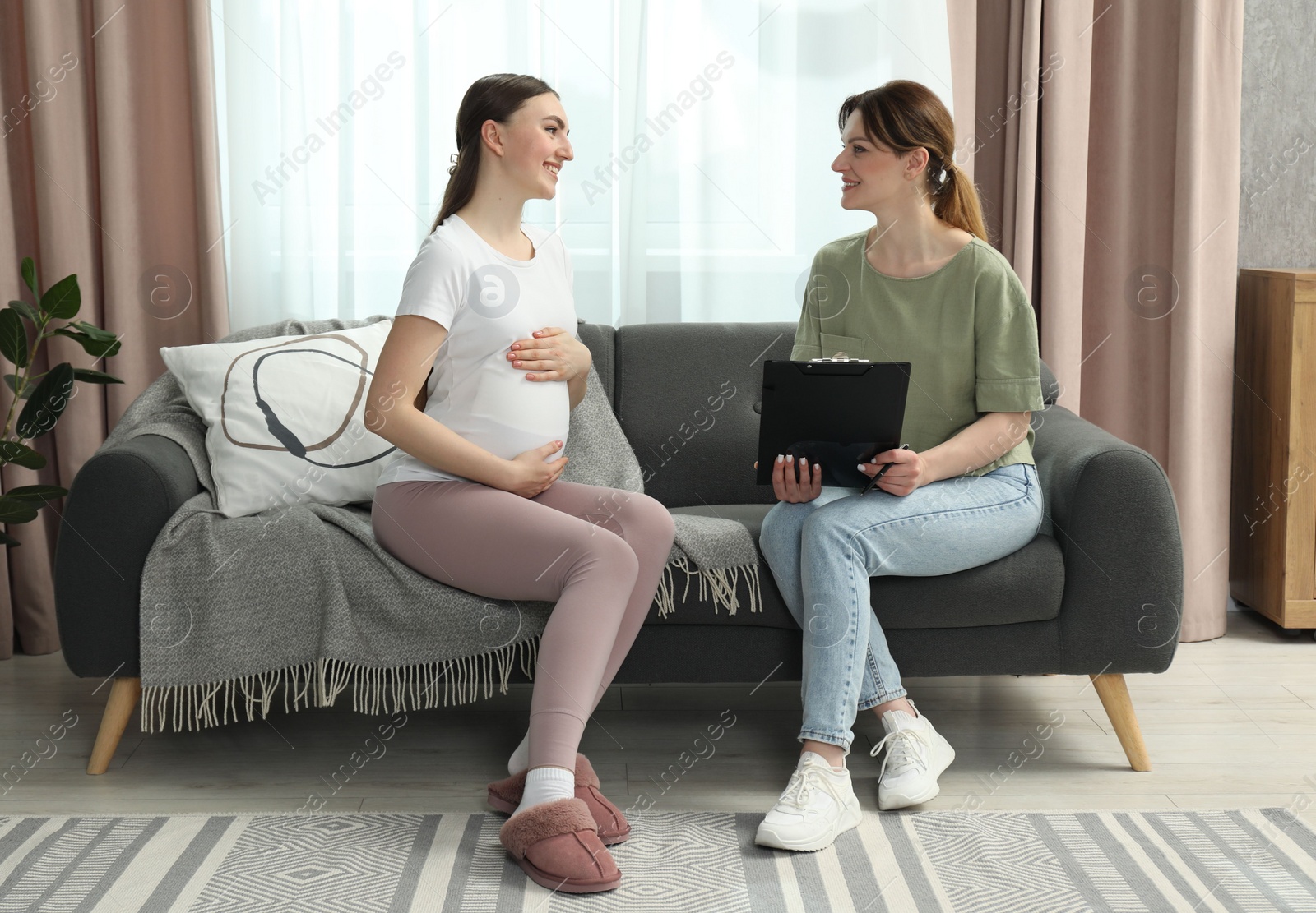 Photo of Doula working with pregnant woman on sofa at home. Preparation for child birth