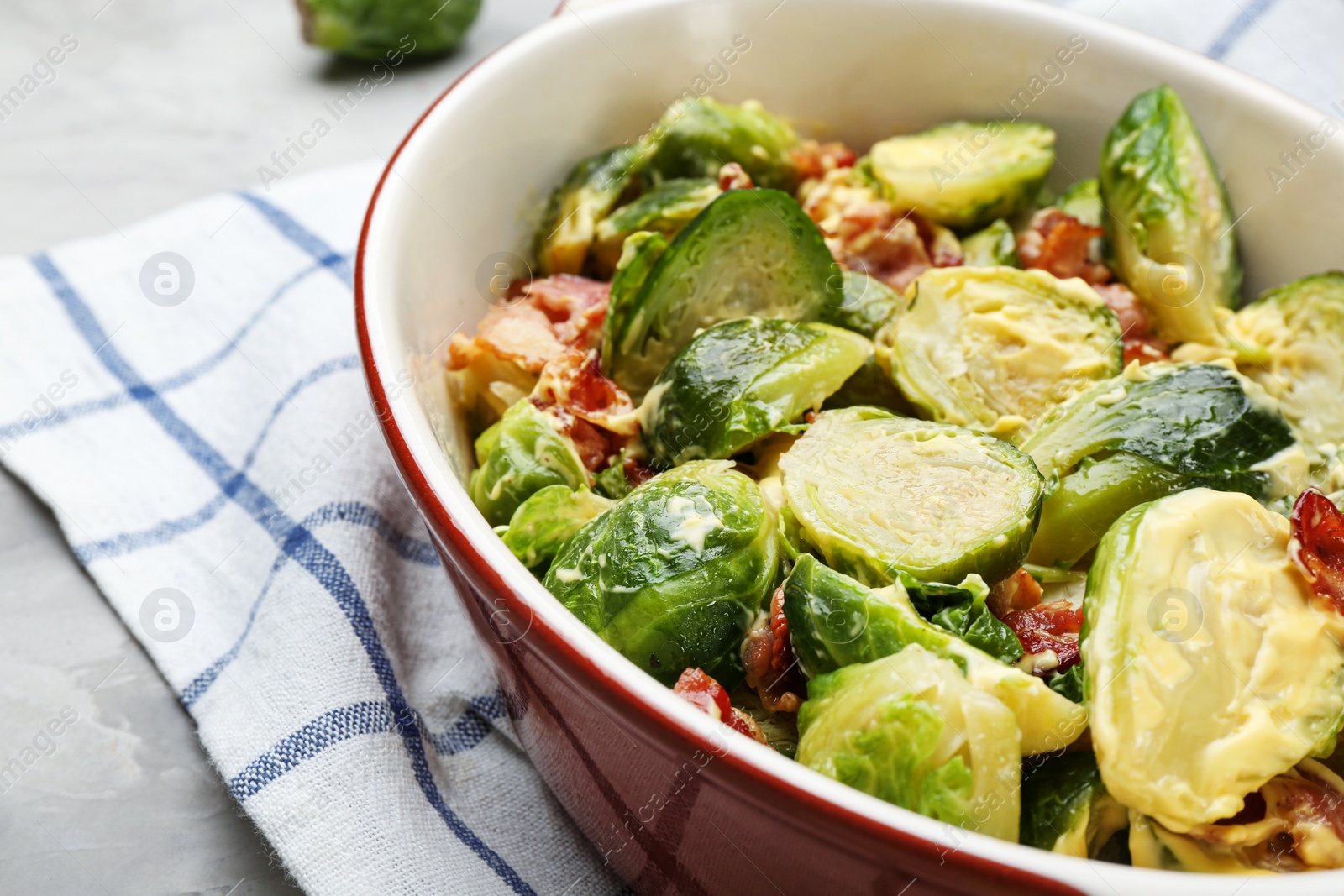 Photo of Delicious Brussels sprouts with bacon in baking pan on grey table, closeup