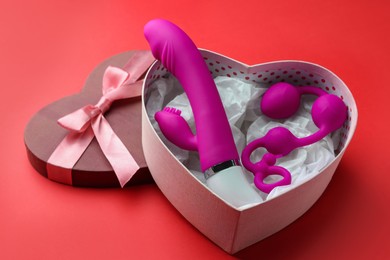 Photo of Gift box with sex toys on red background