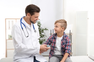 Doctor checking little boy's pulse with medical device in hospital