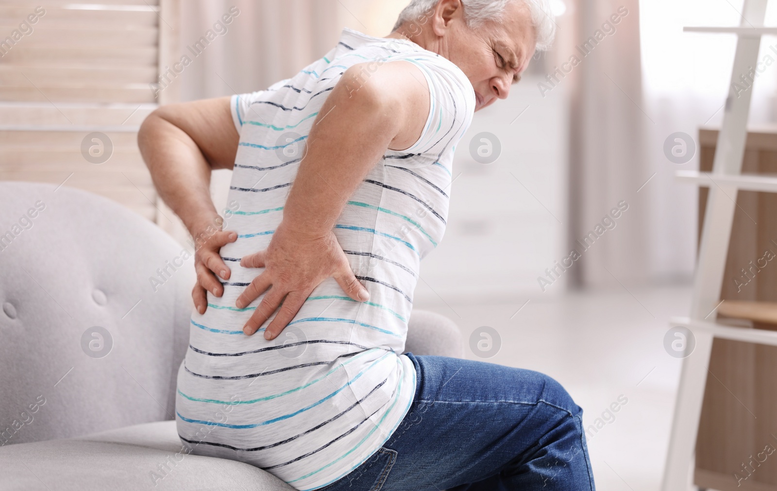 Photo of Senior man suffering from back pain at home