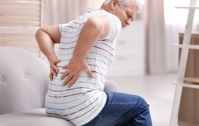 Senior man suffering from back pain at home