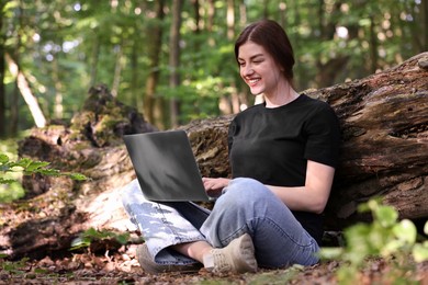 Photo of Smiling freelancer working with laptop in forest, low angle view. Remote job