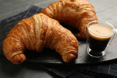 Delicious fresh croissants and cup of coffee on gray table, closeup