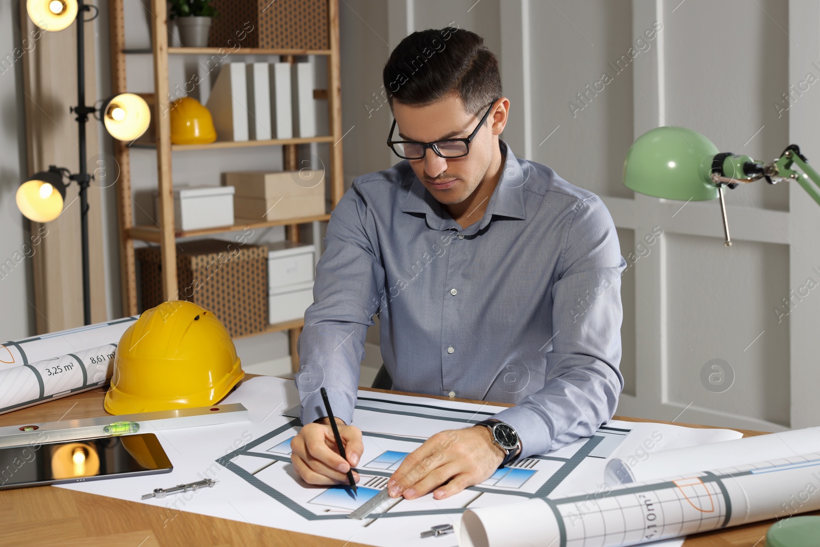 Photo of Architect working with construction drawings in office