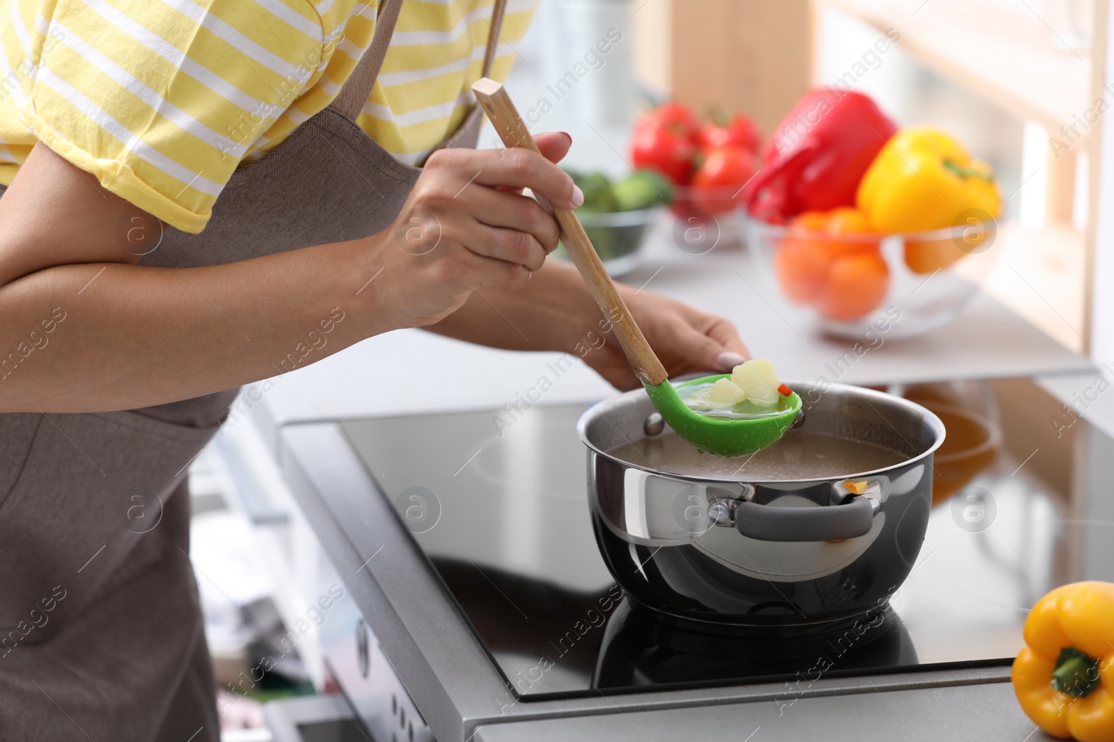 Photo of Young woman cooking tasty soup in kitchen, closeup