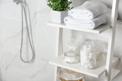 Photo of Shelving unit with cotton balls, swabs and pads in bathroom