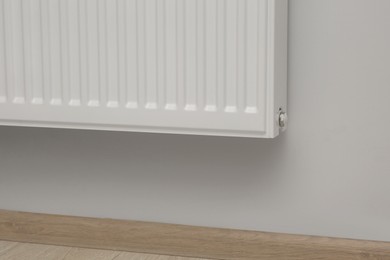 Photo of White wall with modern panel radiator indoors. Heating system