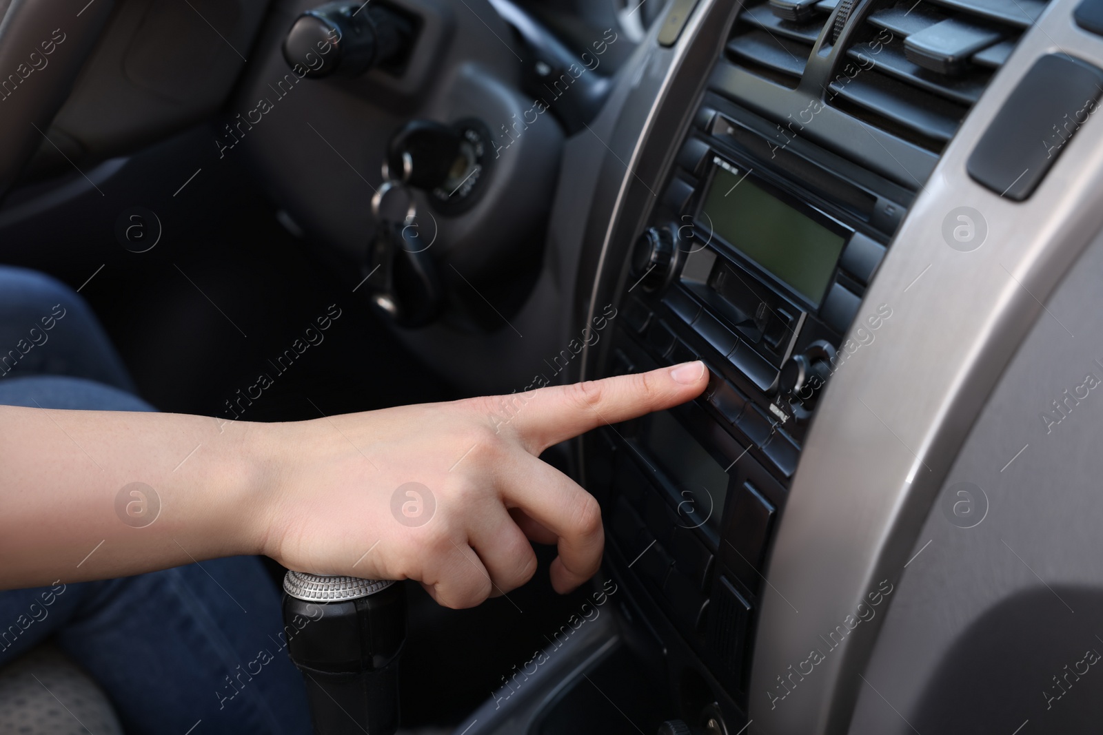 Photo of Choosing favorite radio. Woman pressing button on vehicle audio in car, closeup