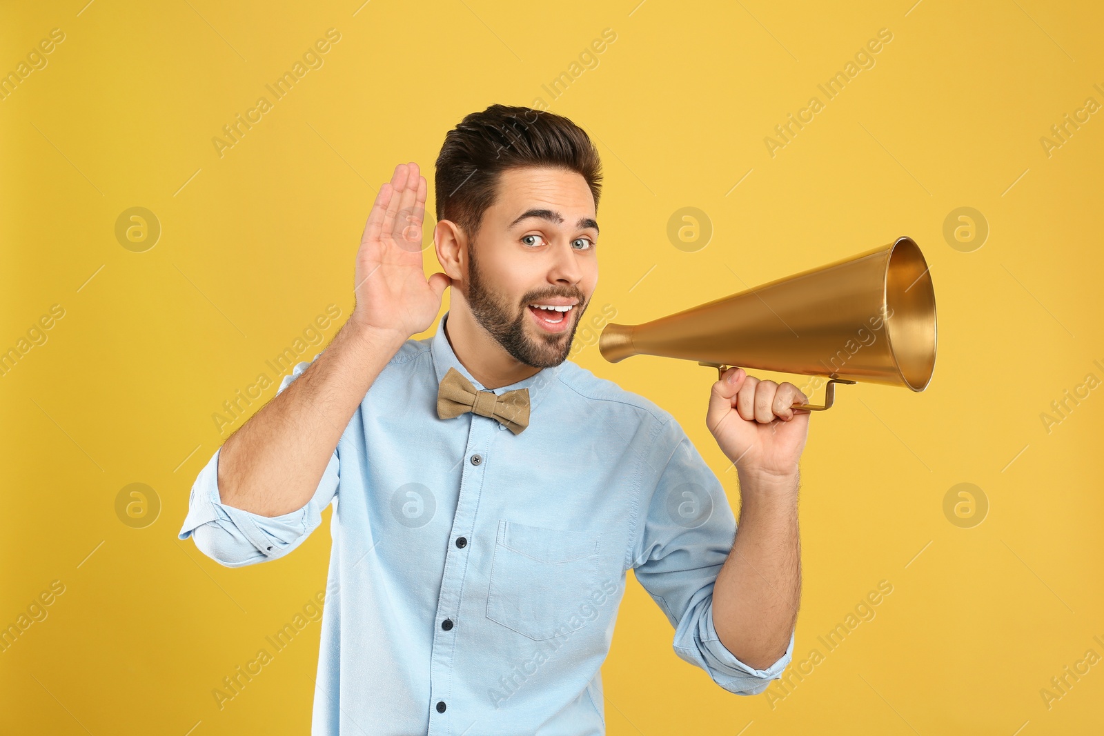 Photo of Young man with megaphone on yellow background
